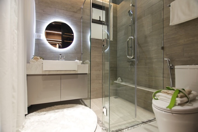 Phòng tắm với nhiều vật liệu làm từ kính và tường ốp đá.