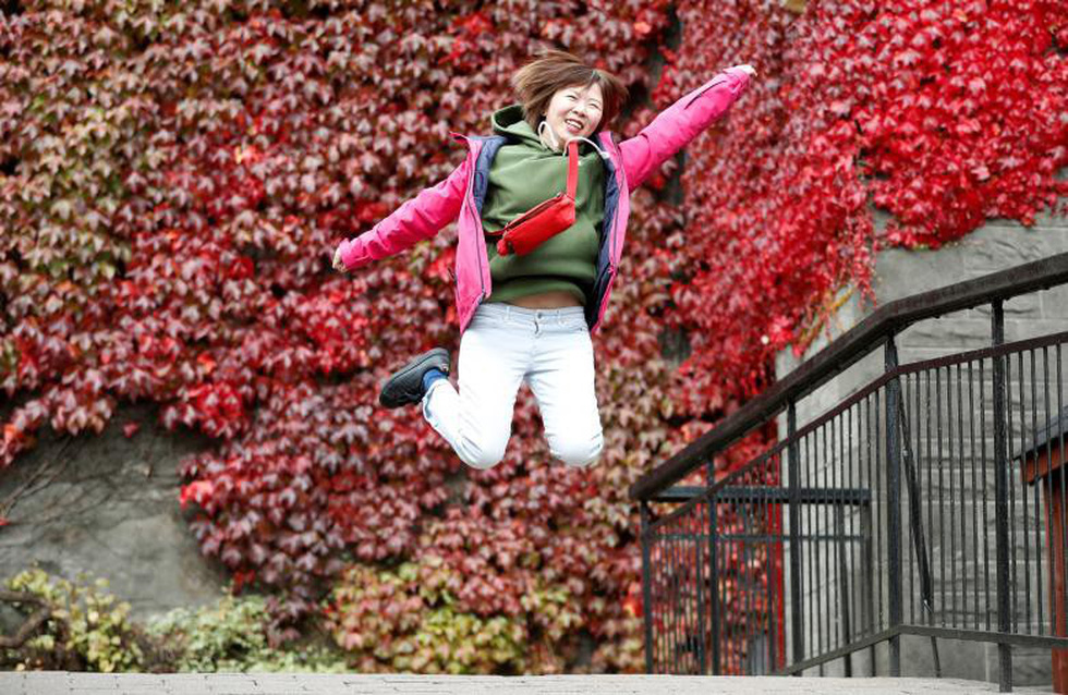 Một nữ du khách nhảy tạo dáng chụp hình trước quang cảnh mùa thu rực sắc đỏ tại vùng Pitlochry, Scotland - Ảnh: Reuters/Russell Cheyne