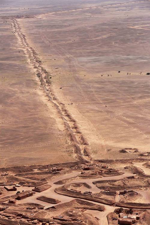 Bức ảnh chụp từ trên không một đoạn của Bức tường Tây Sahara Morocco, công trình dài khoảng 2.700 km chủ yếu làm từ cát chạy qua vùng phía tây Sahara và tây nam Morocco, phân chia vùng tự do và vùng chiếm đóng với lịch sử phức tạp. Các bức tường đá và cát cao khoảng 3 m cùng hố cát, hàng rào và mìn bố trí dọc theo chiều dài khu vực tranh chấp này. Ảnh: Evan Schneider.