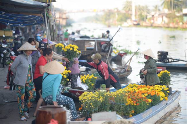 Chị Hồ Thu Lành (bên phải) ở phường 2, thị xã Ngã Năm xuống ghe chọn mua 6 chậu cúc đem về trưng Tết với giá 20.000/ chậu - Ảnh: T.T.D.