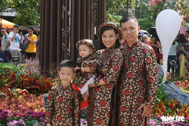 Gia đình anh Lưu Bình Minh (36 tuổi, Q.11) cùng mặc đồng phục áo dài chào đón xuân về tại đường hoa - Ảnh: TUYẾT KIỀU