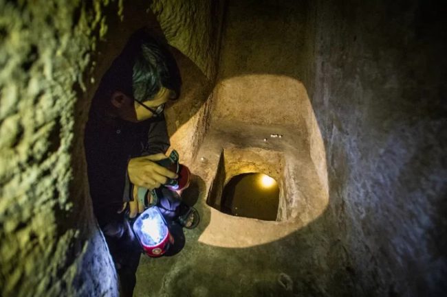Hướng dẫn viên Hoài Nhơn soi đèn pin xuống tầng thứ hai của địa đạo. Anh cho biết, địa đạo có 2 tầng và hệ thống 3 hầm được đào sâu dưới lòng đất từ 3 đến 4 m, nhiều đoạn cao khoảng 1 m, rộng 0,8 m. 
