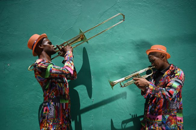 Hai thành viên của ban nhạc địa phương Street Kings chơi kèn trombone và trumpet ở quận Bo-Kaap, Capetown, Nam Phi. Bức ảnh được yêu thích bởi sự kết hợp giữa màu sắc của trang phục và nhạc cụ trên nền tường xanh ngọc bích. Ảnh: Ami Vitale.
