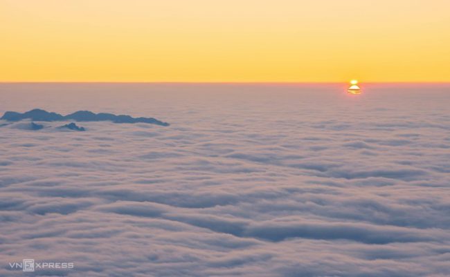Cảnh mặt trời lặn xuống ngang đường chân trời giữa biển mây Fansipan. Từ tháng 10 đến tháng 4, mặt trời lặn sớm, du khách nên căn khoảng thời gian 17h-17h30 để săn cảnh hoàng hôn ở đây.