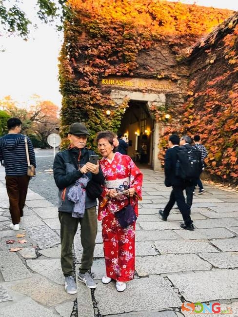 Đôi vợ chồng già diện Kimono chụp hình kỷ niệm ở Kurashiki, với tòa nhà được phủ kín bằng những cây nho leo đang đồng loạt đổi màu lá.
