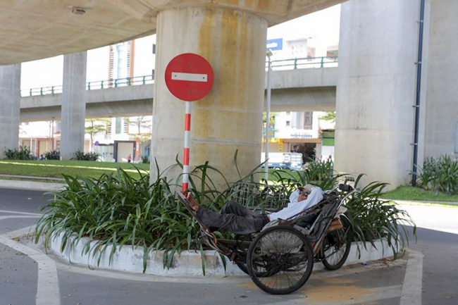 Một người đạp xích lô ở Đà Nẵng tranh thủ ngủ trưa dưới gầm cầu vượt Ngã ba Huế. Ảnh: Nguyễn Đông.