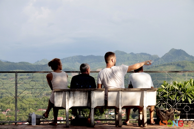 Du khách nước ngoài đang ngồi ngắm cảnh từ đỉnh núi.