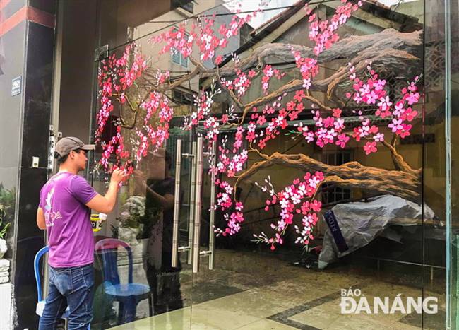 Nhóm vẽ của anh Trần Duy Văn đang vẽ tranh hoa đào trên mặt cửa kính. Ảnh: X.S
