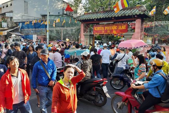 Bên ngoài cổng, xe cộ qua lại khó khăn vì dòng người đổ về chùa đông đúc. Lực lượng dân phòng, trật tự đô thị được huy động để điều tiết giao thông trên đường Mai Thị Lựu.