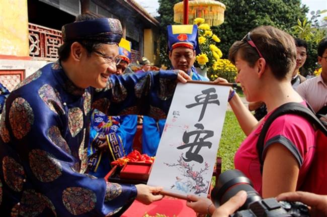 Du khách tham quan Hoàng cung Huế thích thú khi được nhận chữ từ lãnh đạo Trung tâm bảo tồn di tích cố đô Huế. Ảnh: Võ Thạnh