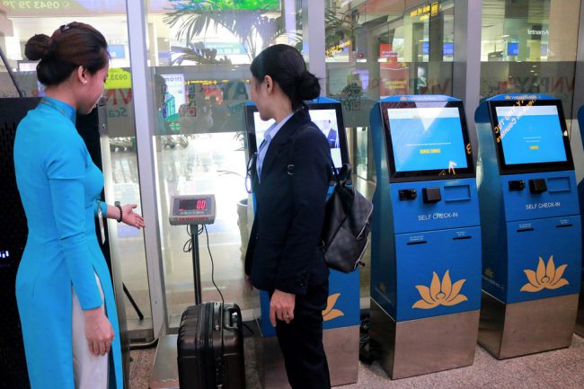 Hành khách tự cân hành lý làm thủ tục bay ở kiôt tại sân bay trong dịp tết - Ảnh: VNA
